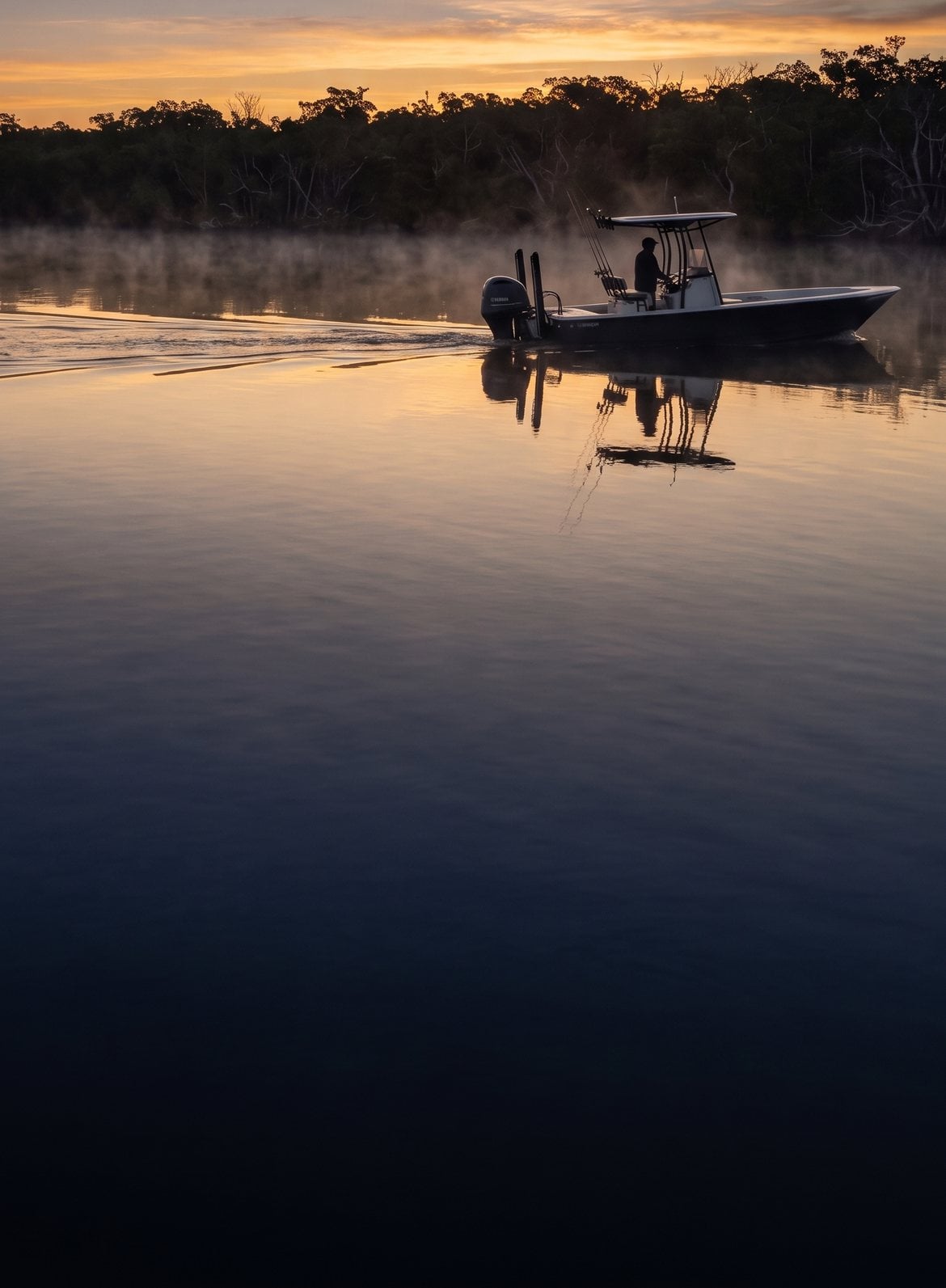 A center console fishing boat idling out past the mangroves at first light