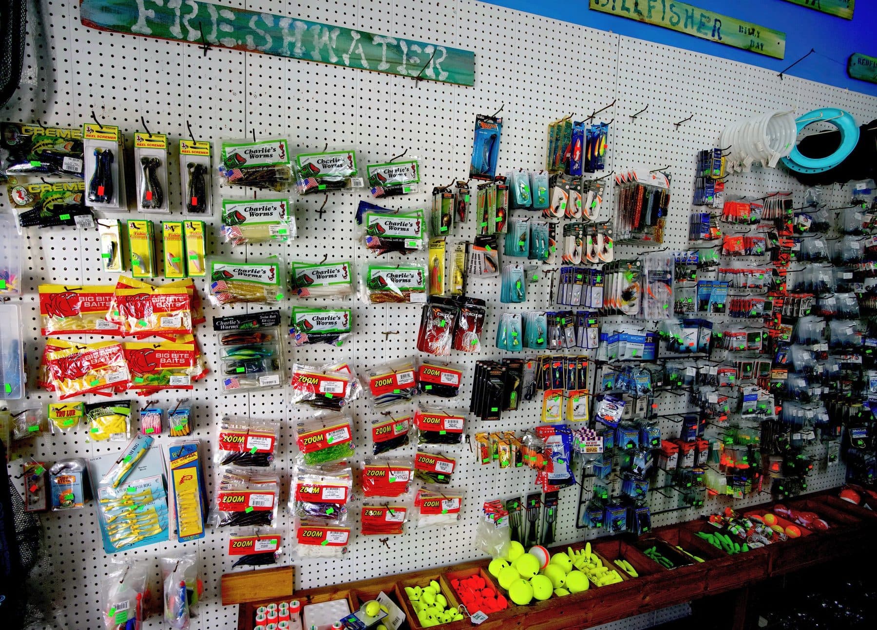 Freshwater pegboard of Zoom and Charlie's Worms soft plastics, spinners and spinnerbaits over wooden bins of foam floats
